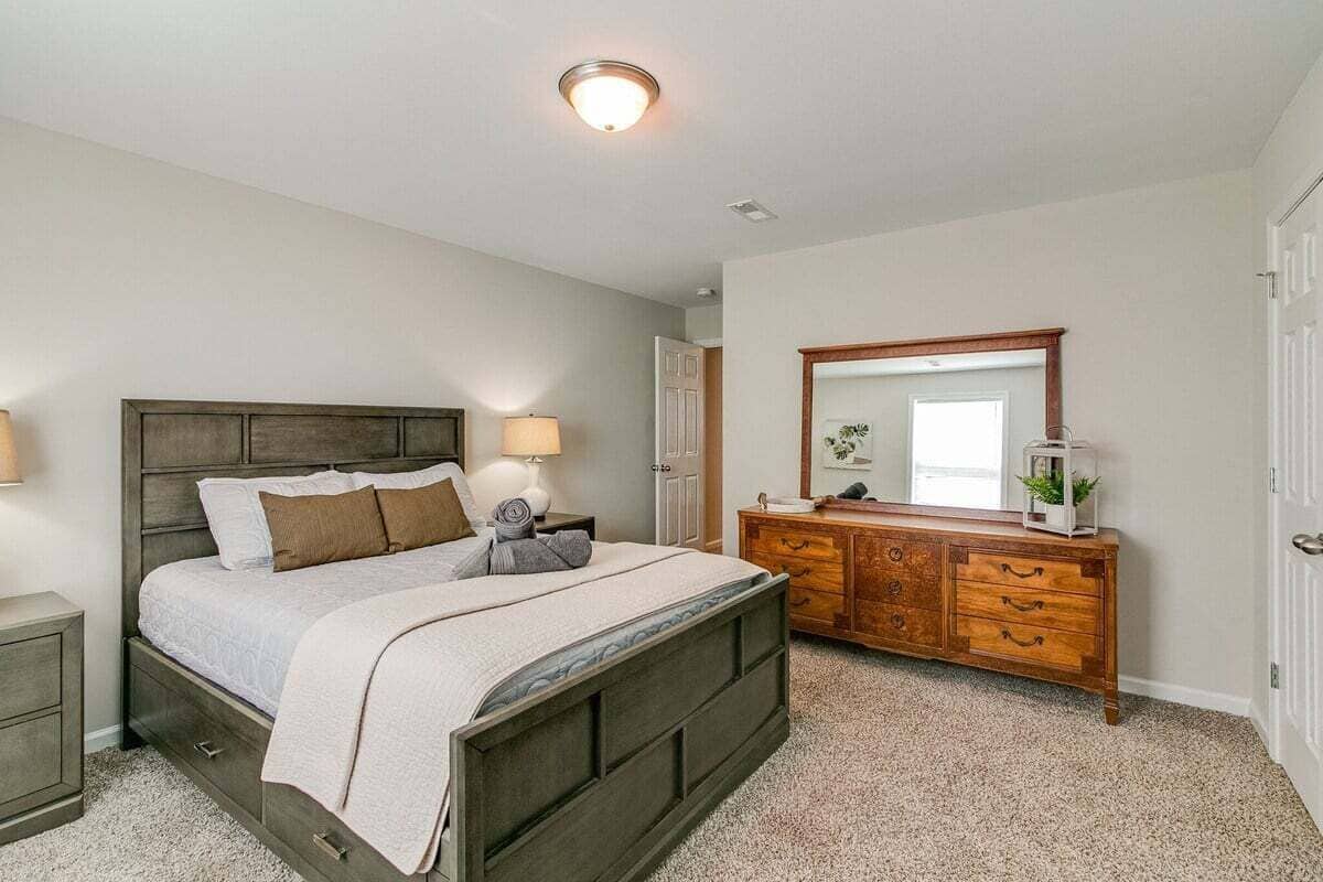 A bedroom with a bed, bedside tables, a dresser, and a mirror.