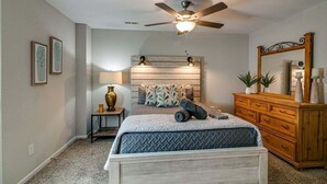 A bedroom with a bed, a ceiling fan, a dresser, a mirror, and a nightstand with a lamp. - Franklin Street (Clarksville)