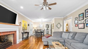 A living room with a fireplace, a grey sofa, a coffee table, and a ceiling fan.