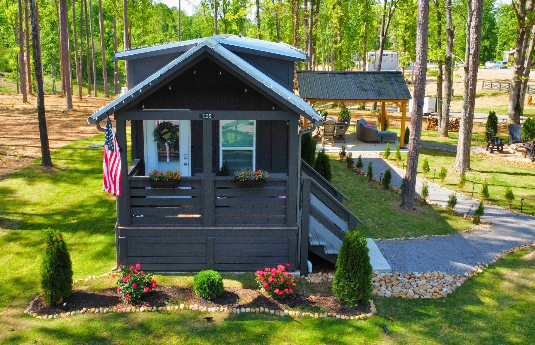 Eine kleine Holzhütte mit Veranda, einer Flagge und einem Schild mit der Nummer 105.