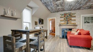 A loft-style living space with a dining area, a red sofa, and a fireplace. - Marion Street (Clarksville)