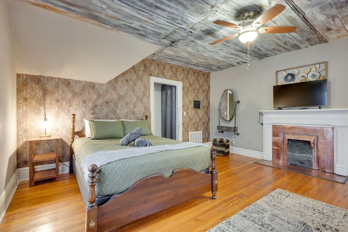 Ein Schlafzimmer mit einem hölzernen Bett, einem Deckenventilator, einem Kamin und einem an der Wand befestigten Fernseher.
