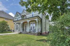 A two-story house with a front porch, a covered entryway, and a visible air conditioning unit.
