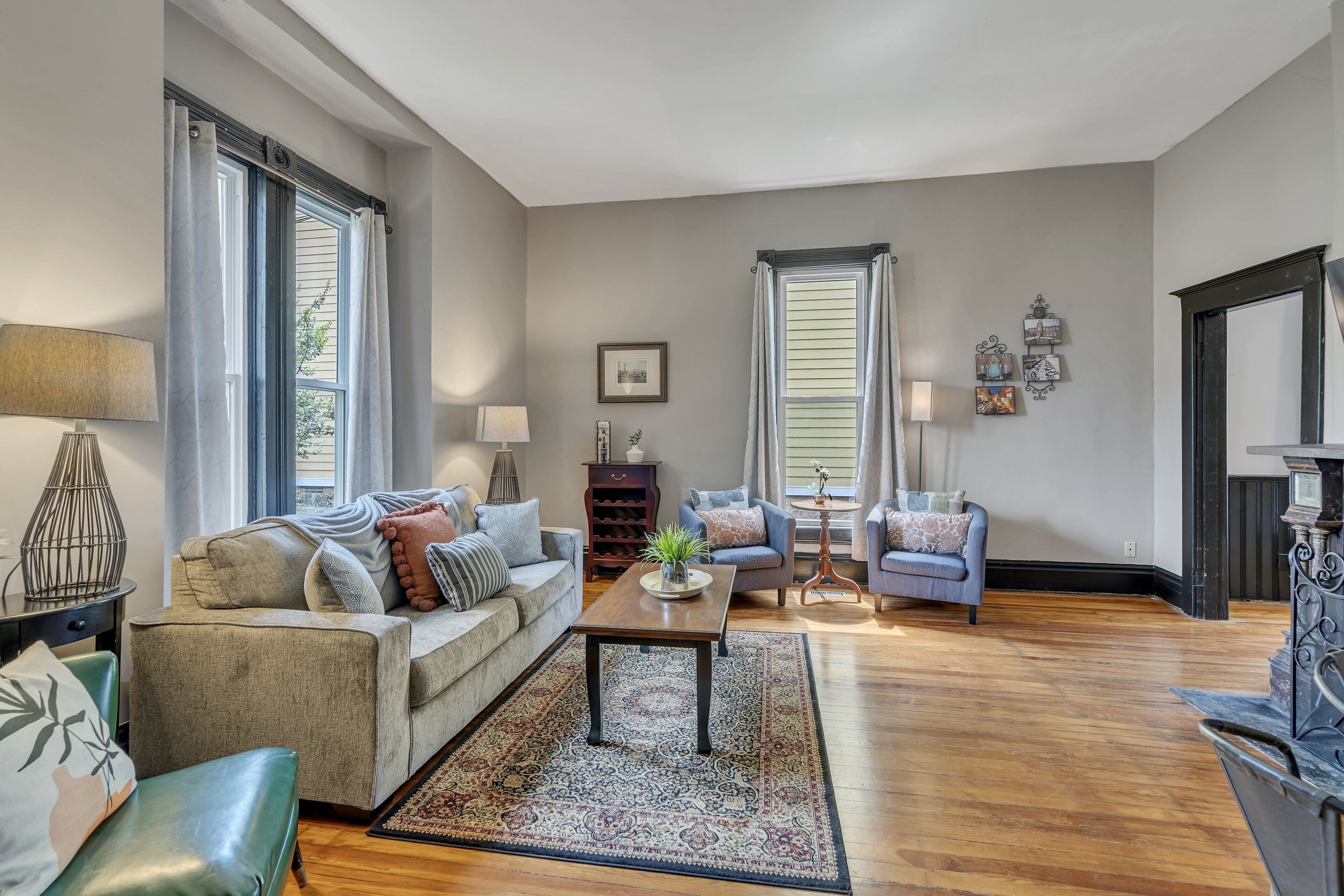 A spacious living room with a sofa, armchairs, a coffee table, and a fireplace.
