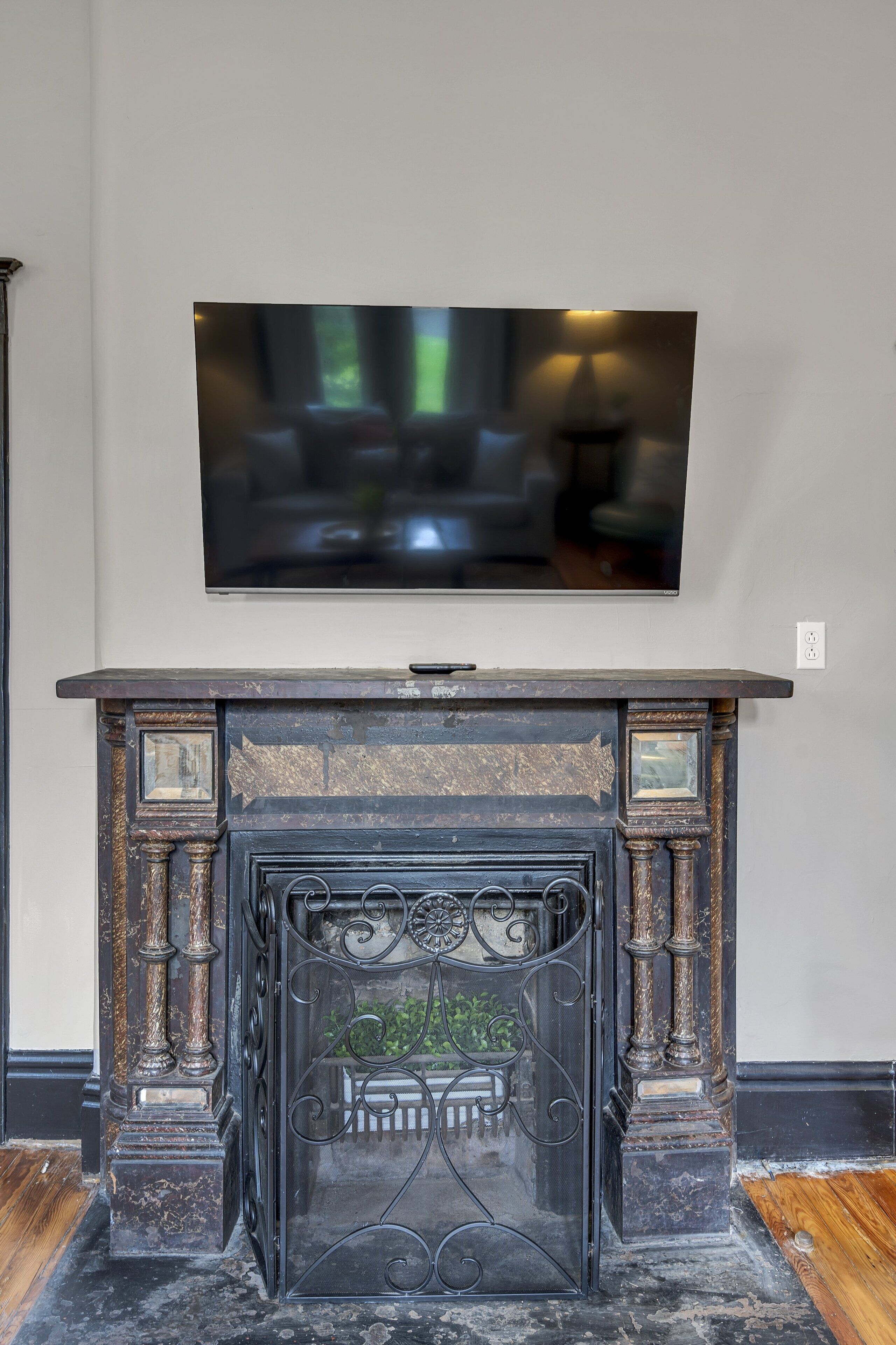 A fireplace with intricate metalwork and a flat-screen TV mounted above it.