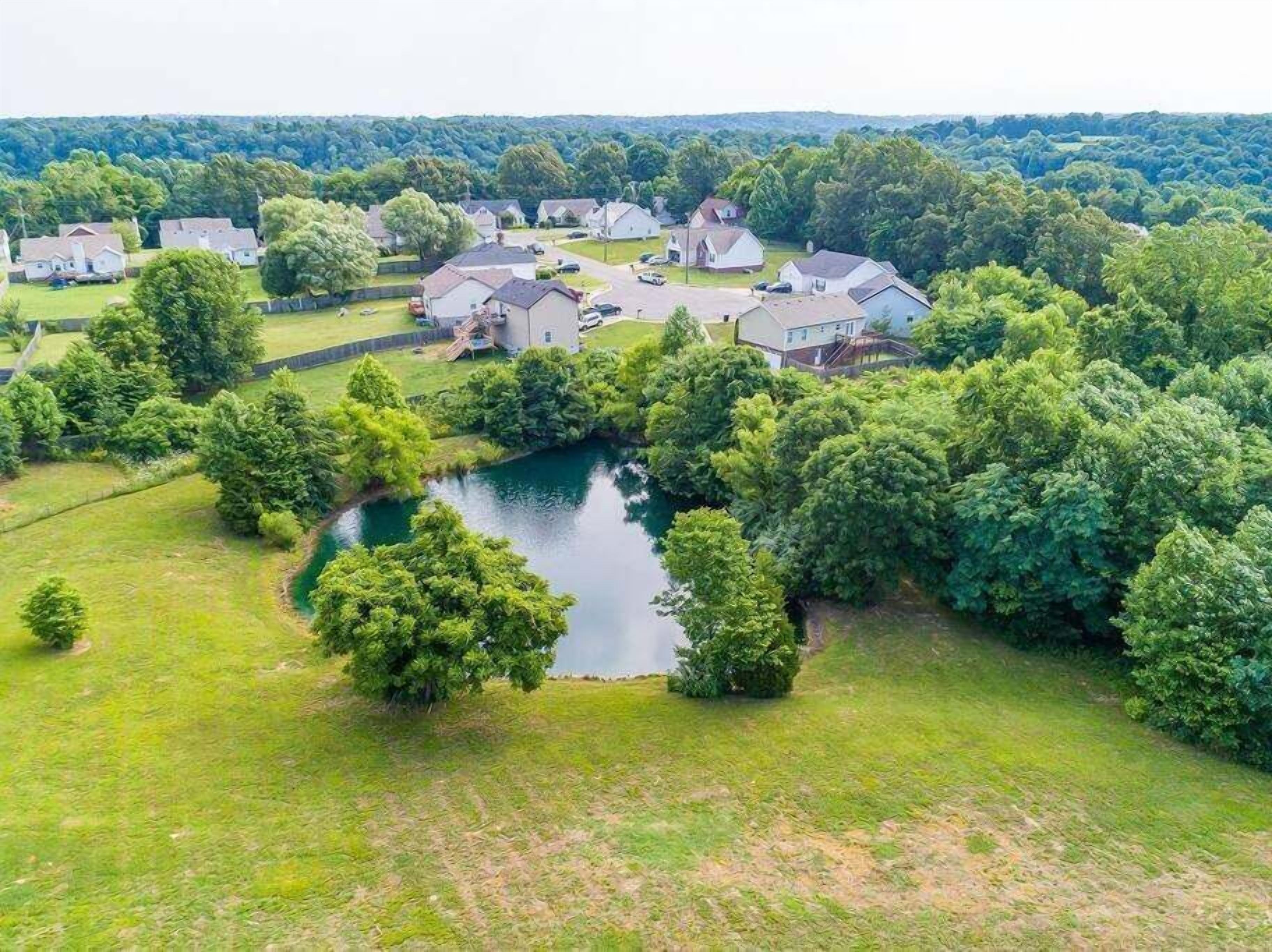 Vista aérea de uma área residencial com casas, um lago e vegetação ao redor.