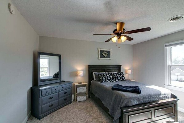 A bedroom with a bed, a dresser, a mirror, a ceiling fan, and a window. - Whitt Lane (Clarksville)