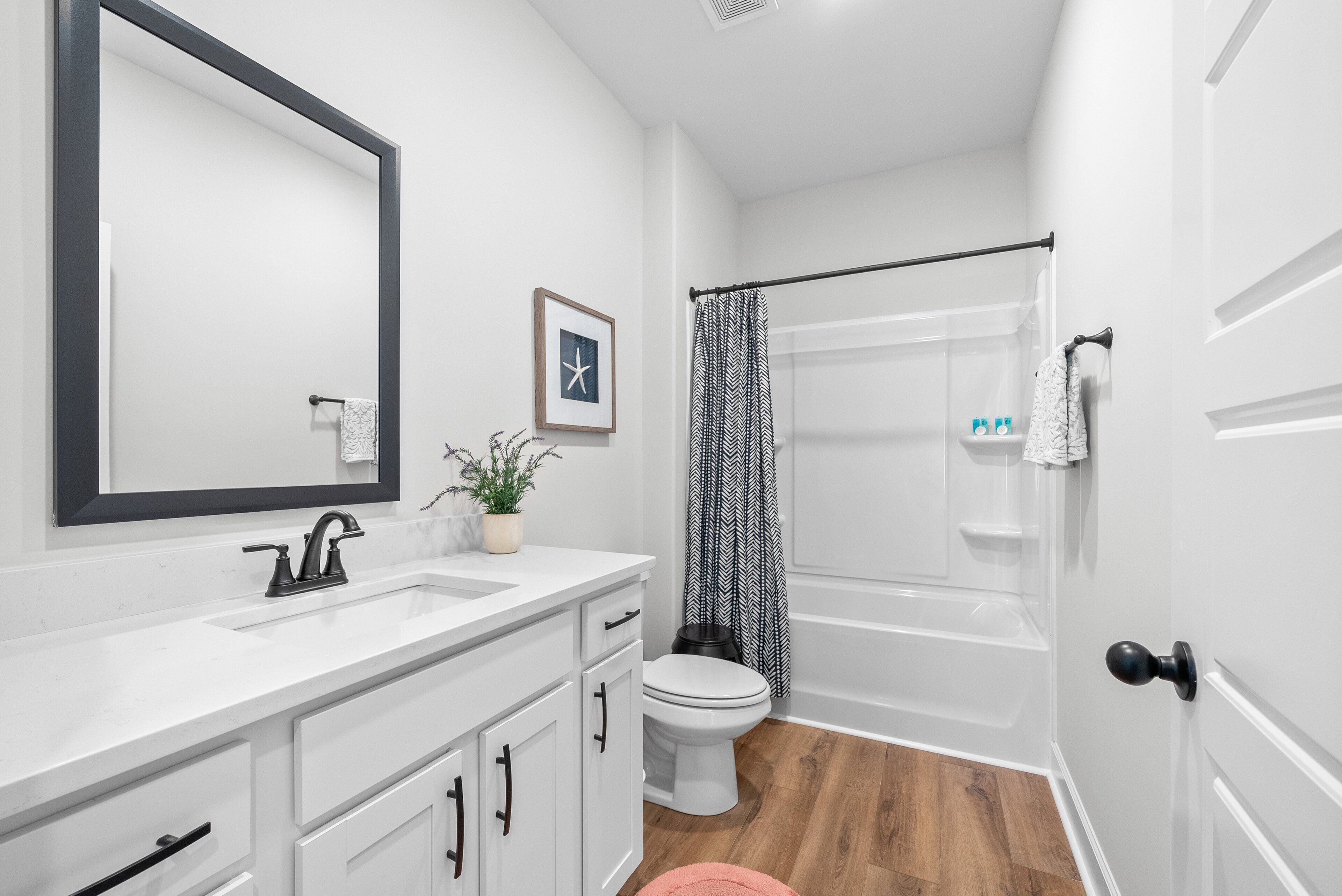 A bathroom with a white sink, a toilet, and a shower area.