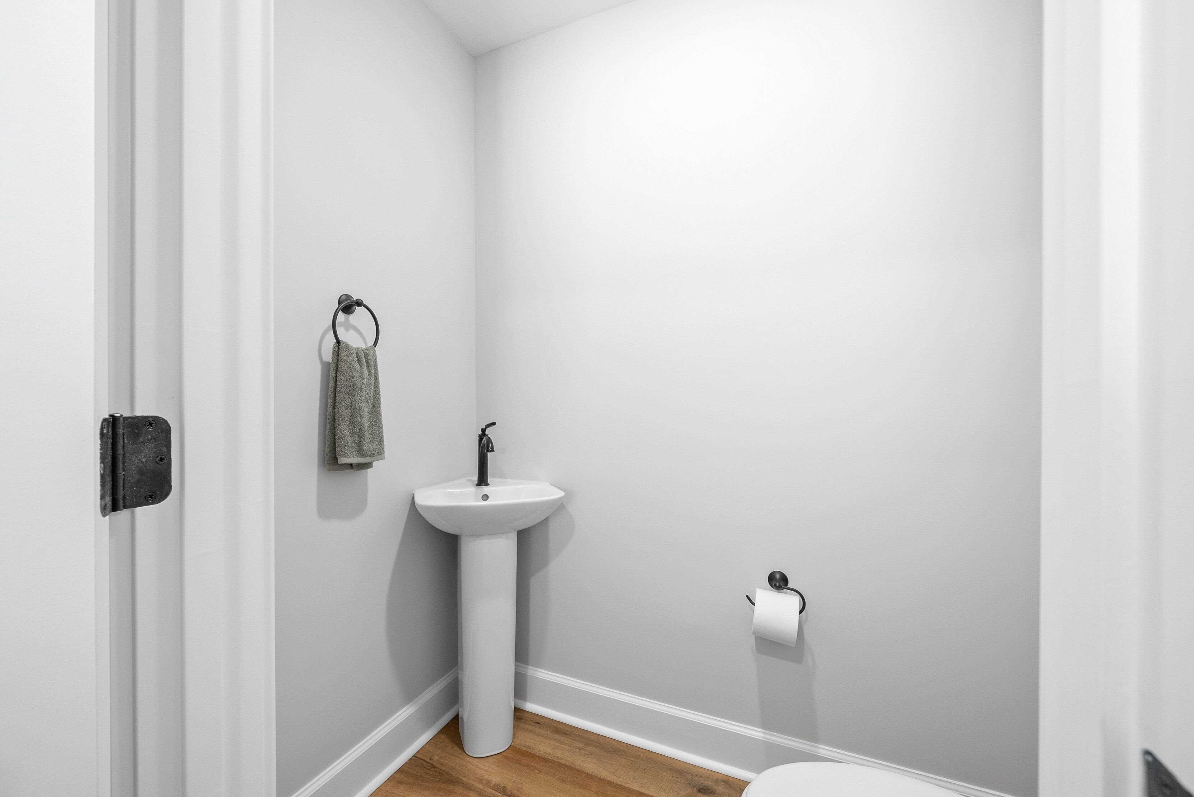 Un baño pequeño y limpio con un lavabo blanco, una toalla colgada en un perchero y un inodoro.