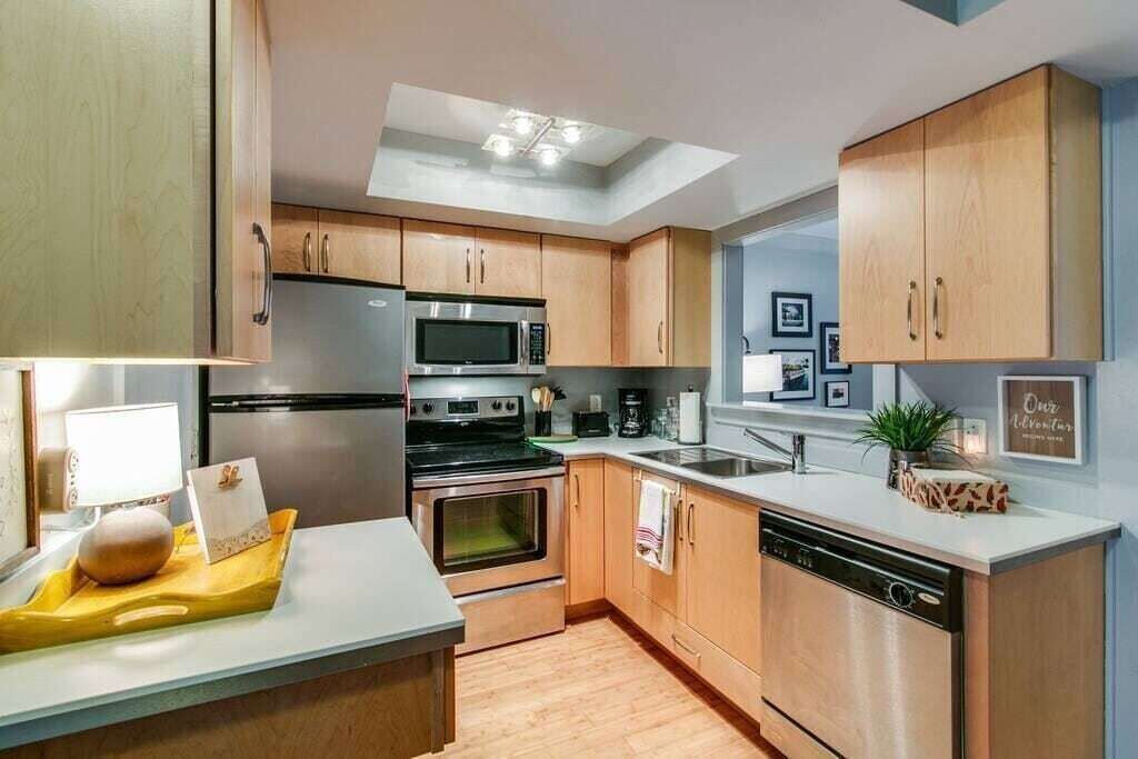 Una cocina moderna con armarios de madera, electrodomésticos de acero inoxidable y un tragaluz.