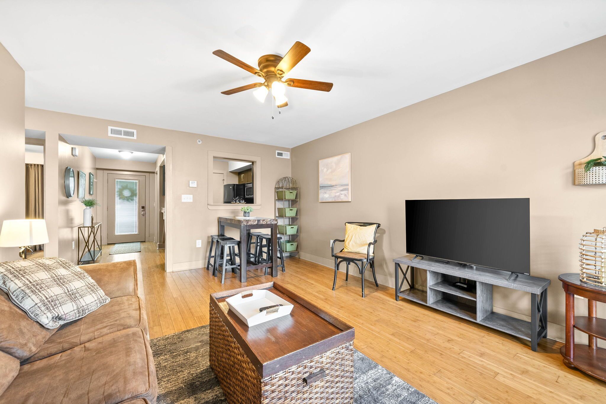 A living room with a ceiling fan, a TV, a sofa, a coffee table, and a dining area with chairs and a table.