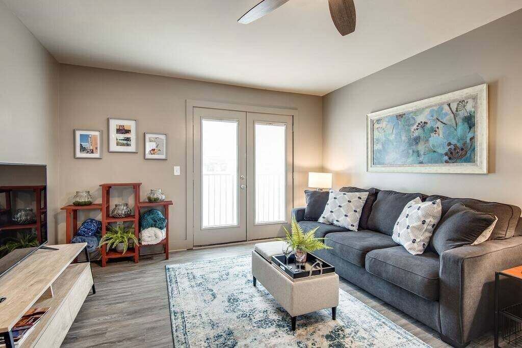 A living room with a grey sofa, a coffee table, a rug, and a painting on the wall.