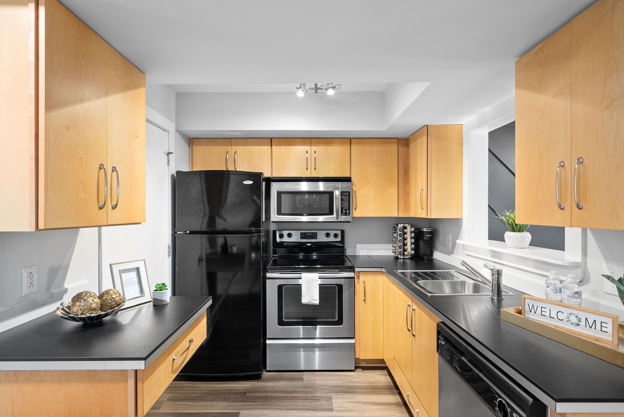 Une cuisine moderne avec des meubles en bois, des appareils en acier inoxydable et un plan de travail noir.