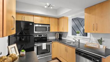 A modern kitchen with wooden cabinets, stainless steel appliances, and a black countertop.