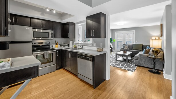 Una cocina moderna con armarios oscuros, electrodomésticos de acero inoxidable y una isla central.