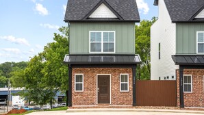 A two-story residential building with a brick facade, a brown front door, and a small porch area. - Urban Rooftop of Downtown (Clarksville)