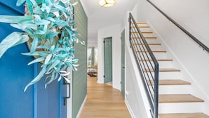 Un escalier avec des marches en bois et une rampe métallique, menant à une pièce dont la porte est verte.