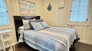 Een slaapkamer met een bed, een nachtkastje, een wandlamp en een schilderij.