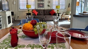 Een eetgedeelte met een tafel gedekt voor twee personen, met een rode fruitschaal, glazen en rode borden.