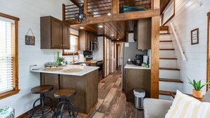 A compact kitchen with wooden accents, a central island, and bar stools. - The Family Truckster (Dover)