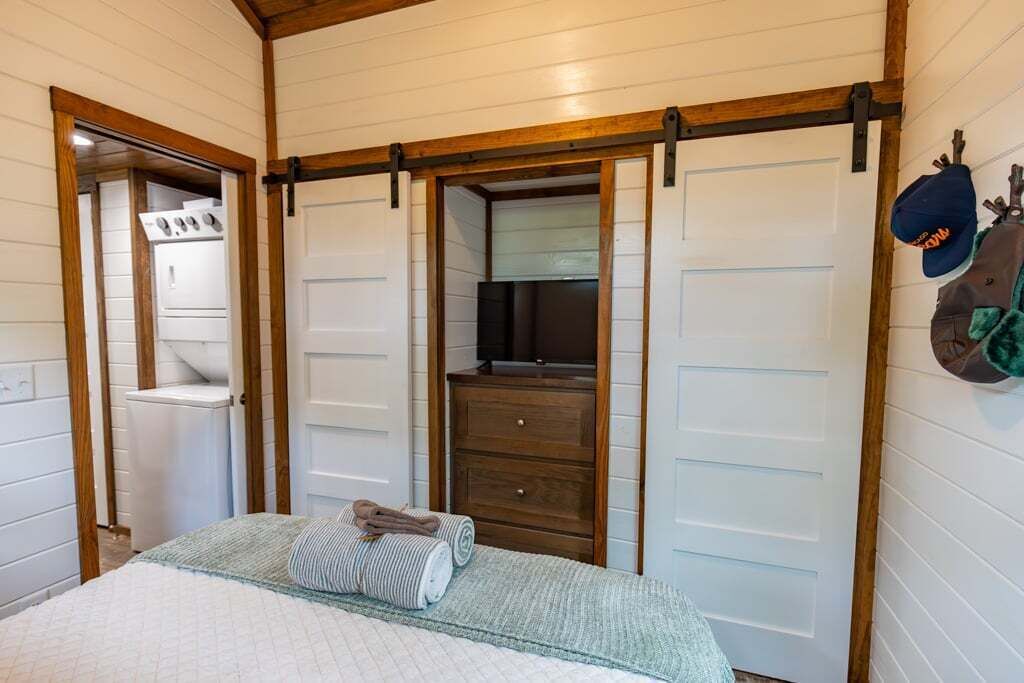 A bedroom with a bed, a wooden dresser, a mirror, and a sliding door closet.