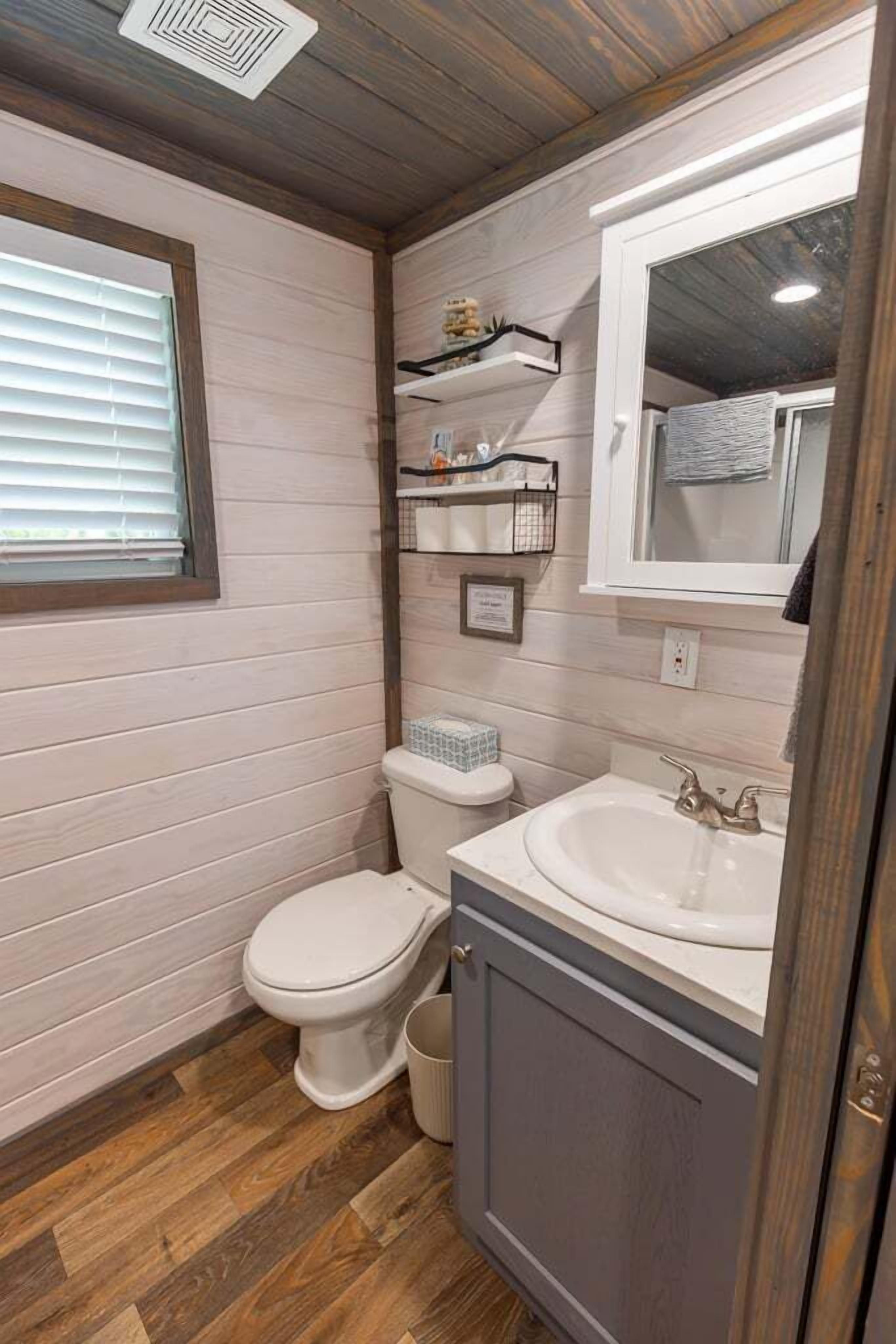 Ein kleines Badezimmer mit Toilette, Waschbecken und Holzboden.