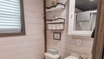 Ein kleines Badezimmer mit Toilette, Waschbecken und Holzboden.