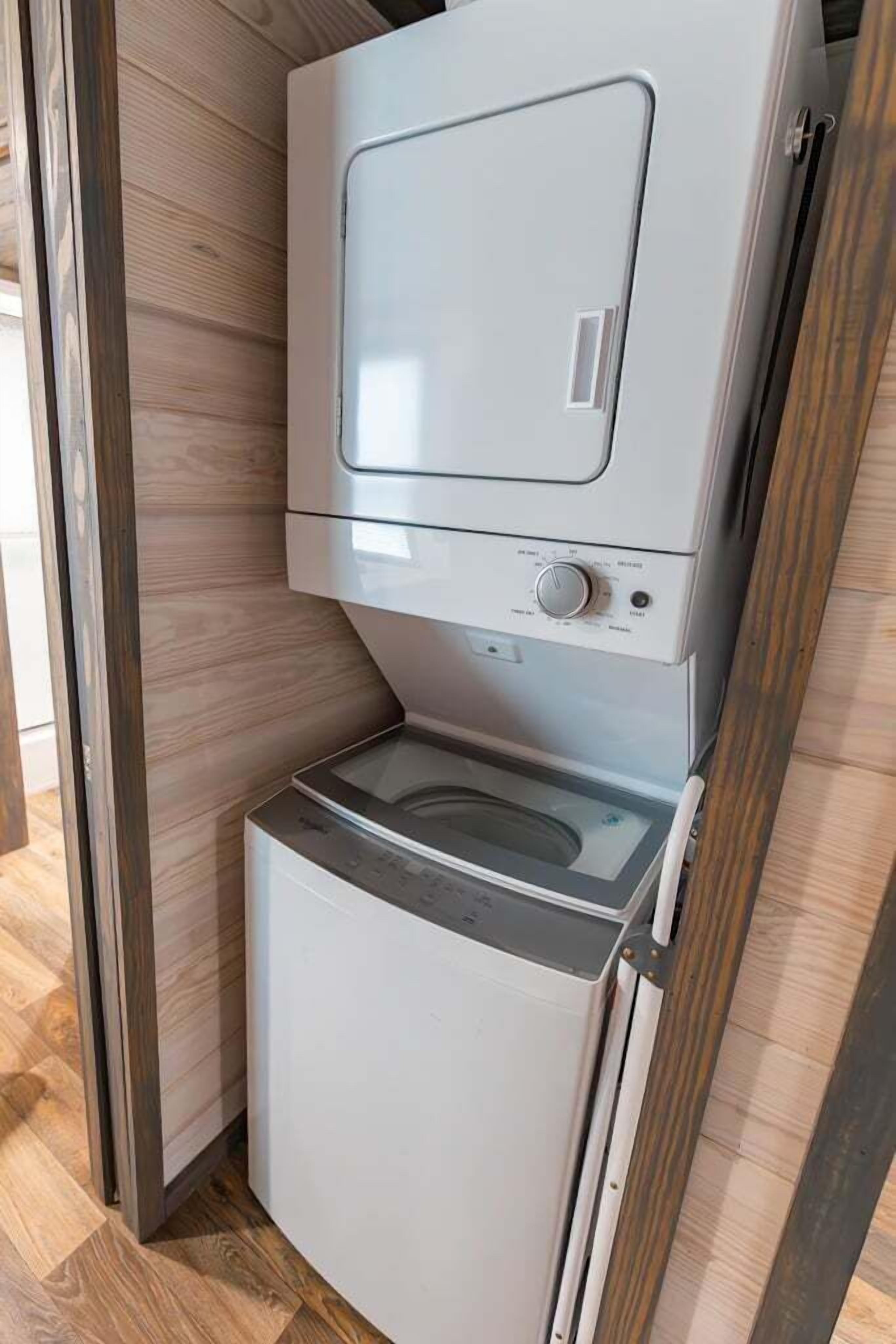 Una cocina compacta y moderna con microondas y horno integrados, suelo de madera y una puerta corredera.