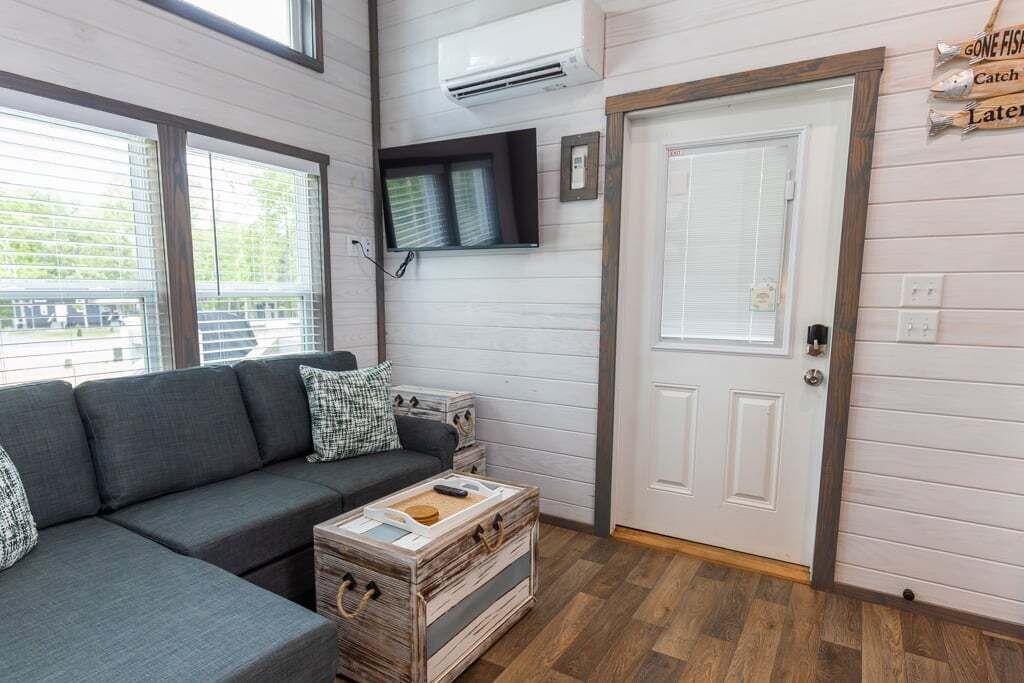 A modern living room with a grey sofa, a wooden coffee table, and a white door.