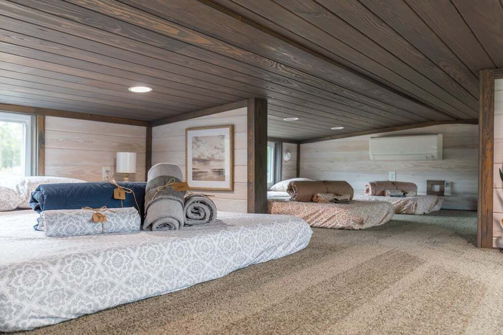 A spacious room with a high ceiling, wooden beams, and a large bed with patterned bedding.