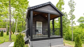 A cabin with a porch, a door, and a small outdoor seating area. - The Nesting Nook (Dover)