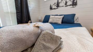 Una cama bien hecha con un edredón doblado y una almohada con el mensaje 'welcome home'.