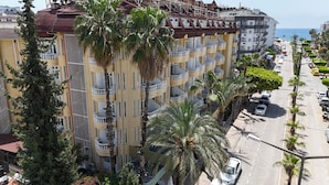 Un hotel de varios pisos con balcones, un estacionamiento y vista al mar.