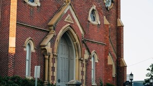 A red brick church with a large circular stained glass window, a prominent entrance with an arched doorway, and a bell tower. - Kim's Place on Cigar Hill (Clarksville)