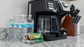 A coffee maker, water bottles, and a snack package on a kitchen counter.