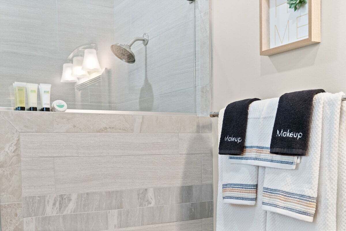 Une salle de bain avec une douche, un miroir et une étagère où sont rangés les articles de toilette.