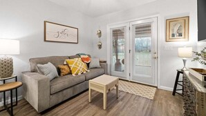 Ein Wohnzimmer mit grauem Sofa, einem kleinen Couchtisch, einer Lampe und einem gerahmten Kunstwerk an der Wand.