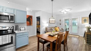 Eine moderne Küche mit hellblauen Schränken, einer Edelstahl-Mikrowelle und einem Essbereich mit einem Holztisch und Stühlen.
