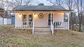 Ein kleines Haus mit Veranda, einem Radzierdekor und Lichterketten.