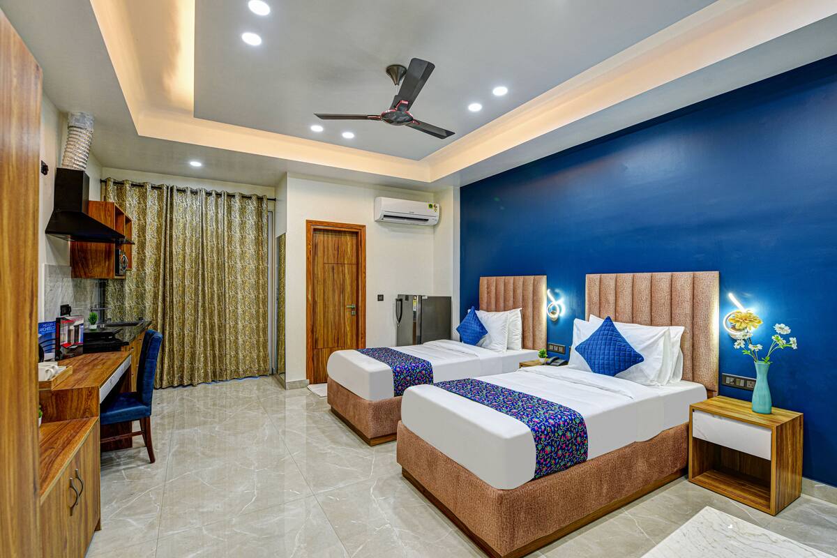 A hotel room with two beds, a desk, a ceiling fan, and an air conditioning unit.