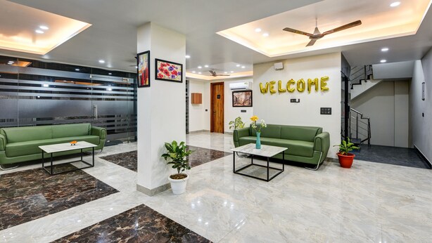 A modern lobby with green sofas, white coffee tables, and a 'WELCOME' sign. - MEHU RESIDENCY (Gurugram)
