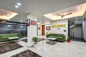 A modern lobby with green sofas, white coffee tables, and a 'WELCOME' sign. - MEHU RESIDENCY (Gurugram)