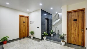 A modern hotel lobby with marble flooring, wooden doors, and potted plants. - MEHU RESIDENCY (Gurugram)