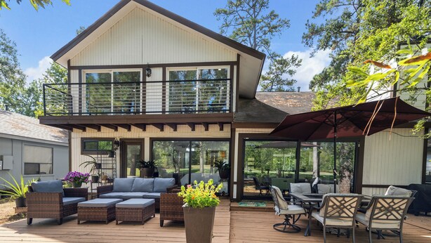 A two-story house with a deck, outdoor furniture, and a large planter.