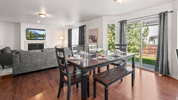 Ein modernes Wohnzimmer mit Essbereich, Kamin und großem Fenster mit Blick auf einen Garten.