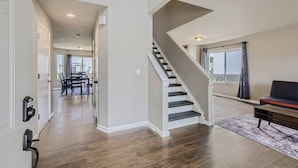 Ein geräumiger Wohnbereich mit Treppe, Holzdielen und einem Essbereich im Hintergrund.