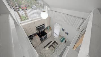 A kitchen with a built-in oven, a sink, and a window overlooking a parking area.