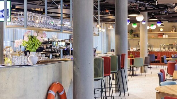 Un interno moderno con angolo bar, posti a sedere e attrezzature da cucina a vista.