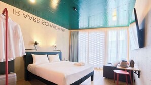 Una camera d'albergo con un letto, una scrivania, una sedia, un armadio e una finestra con tende.