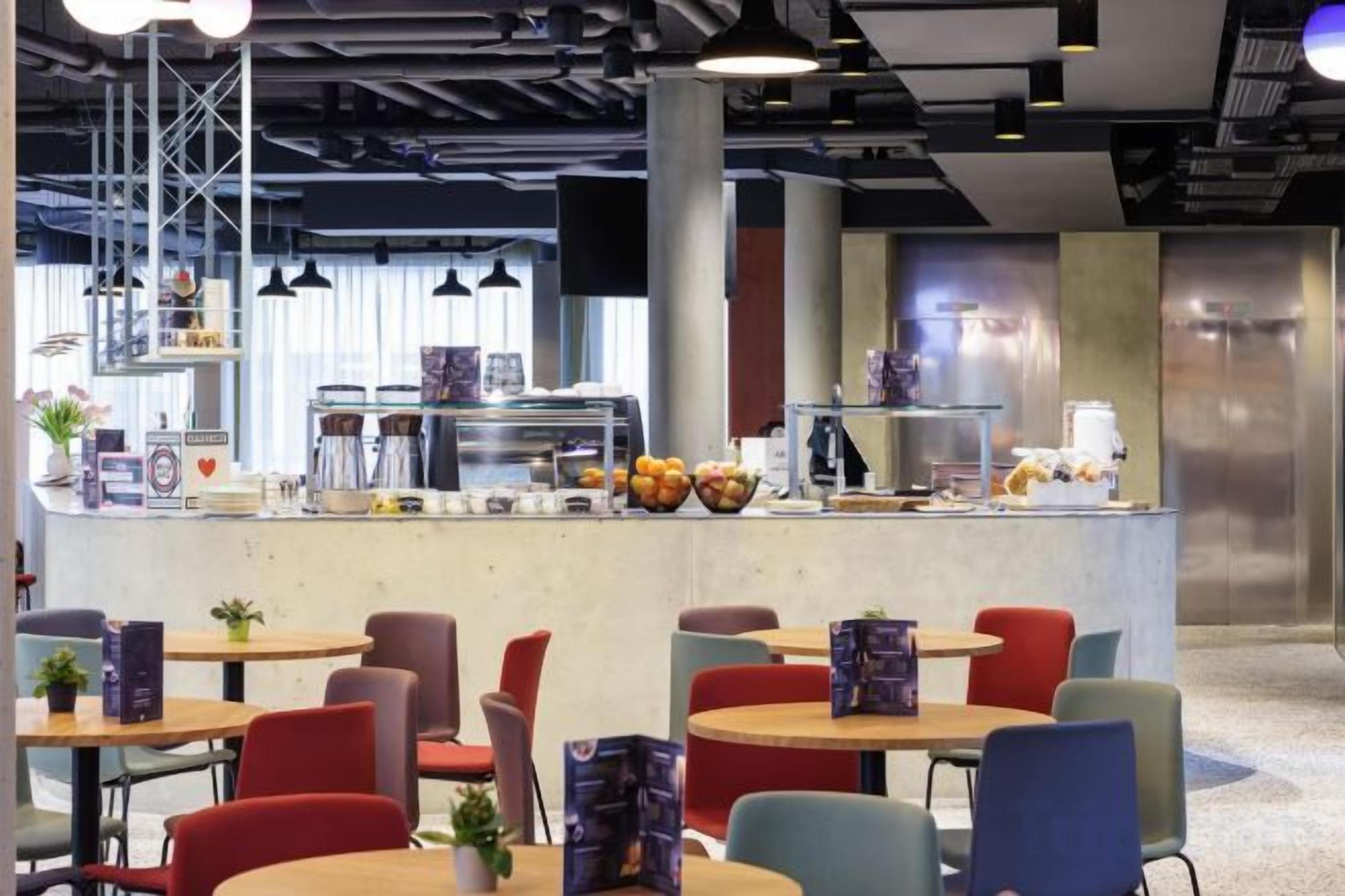 Un café moderne avec un comptoir central, un espace salon et du matériel de cuisine visible.